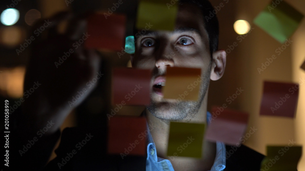 Business man working late building new ideas with sticky note paper on window Business man working late building new ideas with sticky note paper on window