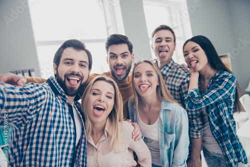 Self portrait of stylish foolish comic attractive crazy funny economists, students, financiers, lawyers in casual outfit shooting selfie on front camera showing tongue out, embracing © deagreez