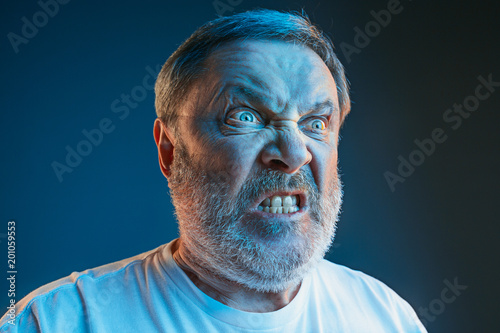 The senior emotional angry man screaming on blue studio background photo