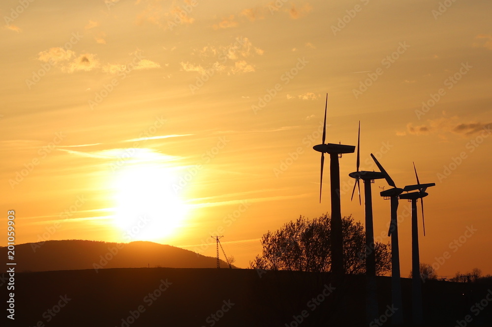 Obraz premium Wind power station in sunset. Romantic evening and modern technologies of ecologically clean electricity. Protection of the environment. Bright Future. An alternative way of extracting energy.