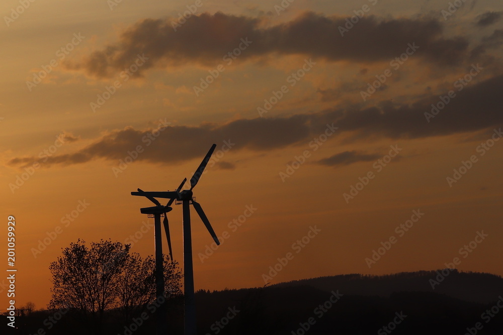 Obraz premium Wind power station in sunset. Romantic evening and modern technologies of ecologically clean electricity. Protection of the environment. Bright Future. An alternative way of extracting energy.