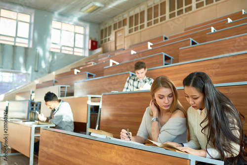 Φωτογραφία Multi-ethnic  group of students sitting at separate tables in lecture hall of mo