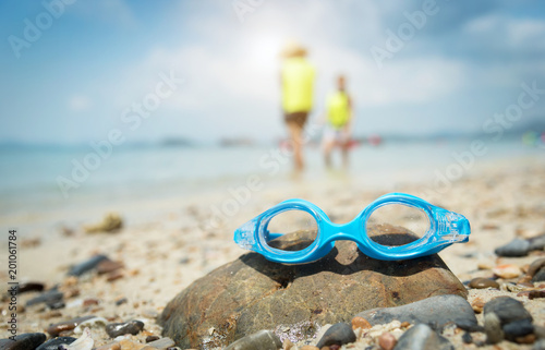 Swimming goggles in the sand on sea background