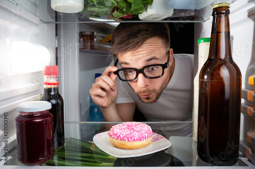 Mann entdeckt einen Donut im Kühlschrank photo