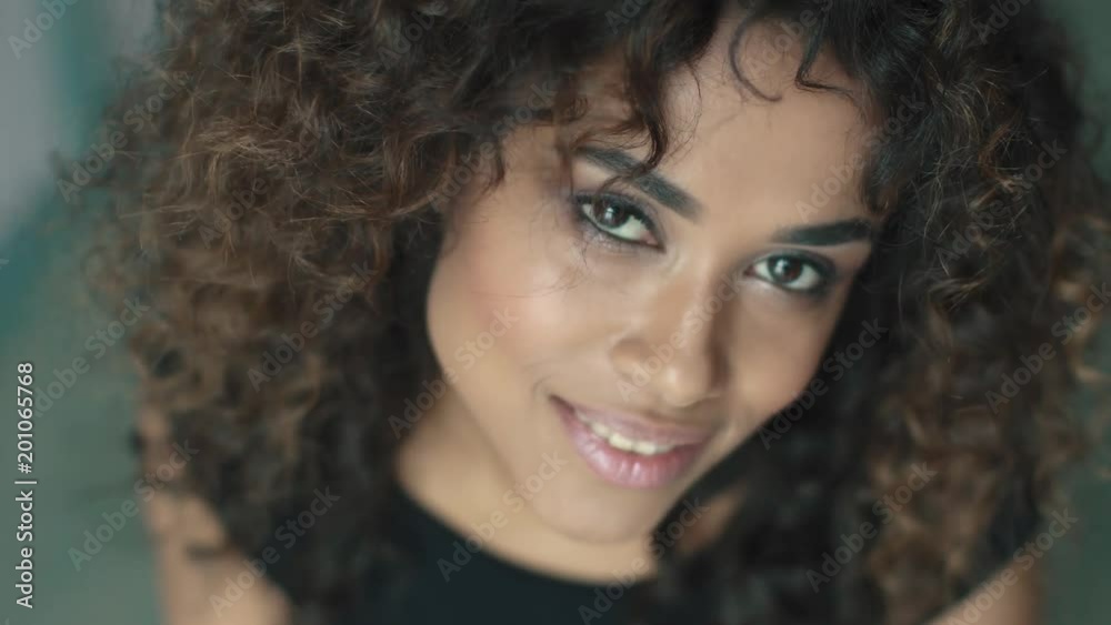 young hispanic woman with curly hair and brown eyes smiling at the camera young hispanic woman with curly hair and brown eyes smiling at the camera