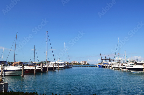 Luxury boats moored at a marina in the south beach section of Miami Beach,Florida with luxury island condominiums in the distant background .