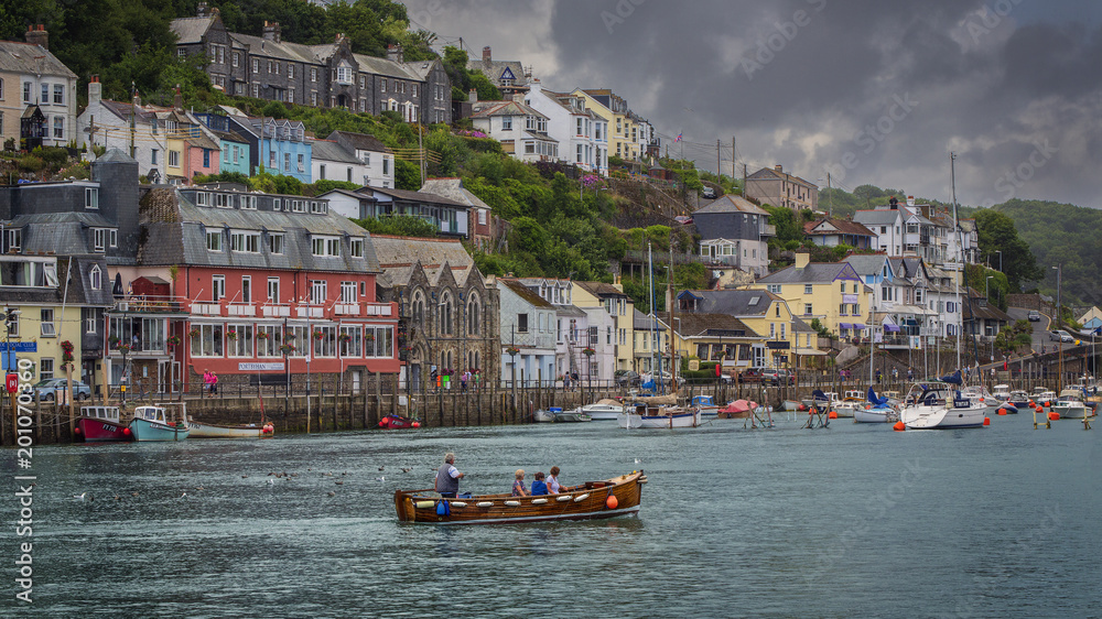 Water taxi crossing the river at Looe Cornwall with colourful houses and other boats