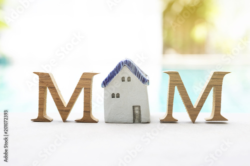 Mother's day concept, Wooden M text with vintage style ceramic house over blurred swimming pool background, outdoor day light