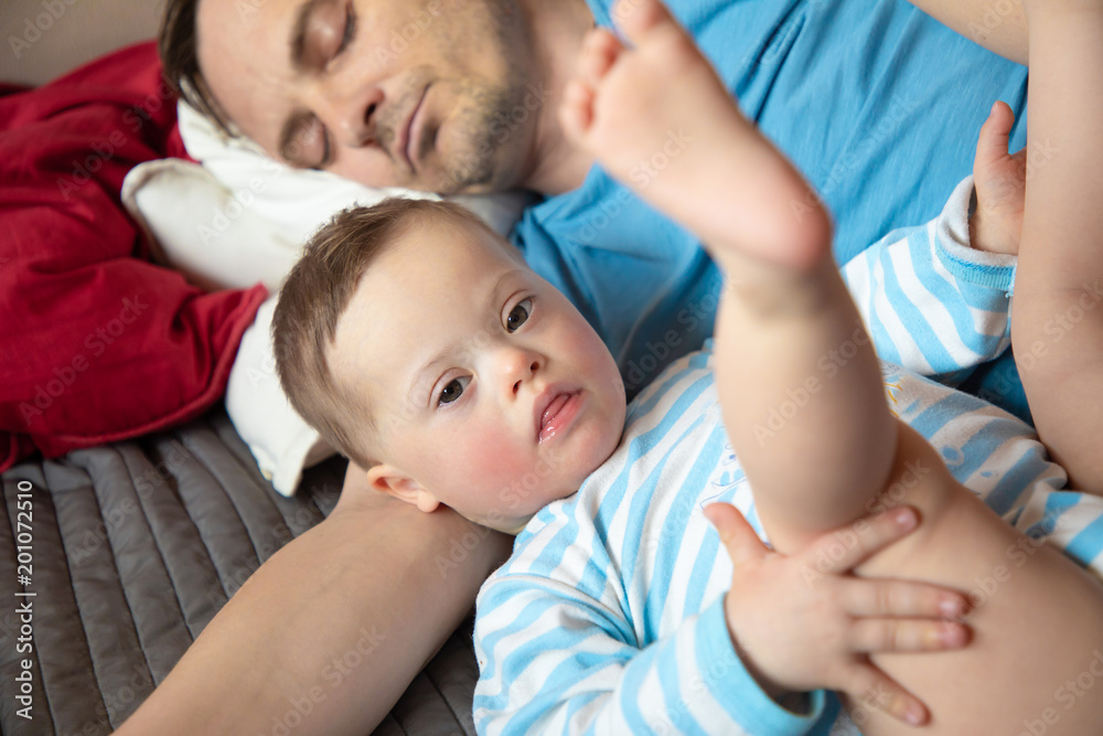 Cute baby boy with Down syndrome playing with dad on in home living room Cute baby boy with Down syndrome playing with dad on in home living room