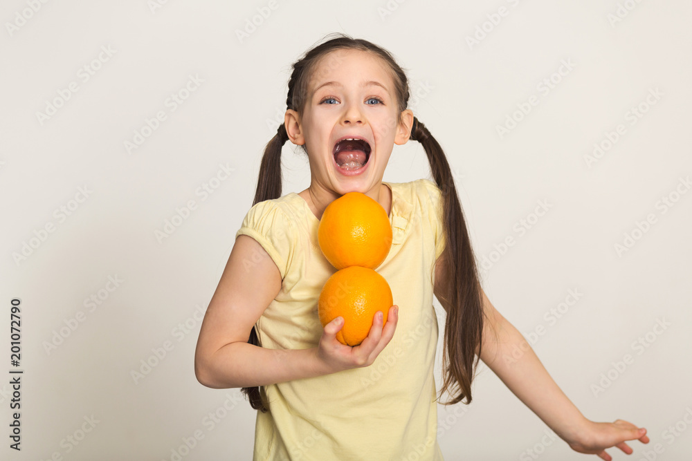 Happy little girl having fun with oranges over white background Happy little girl having fun with oranges over white background