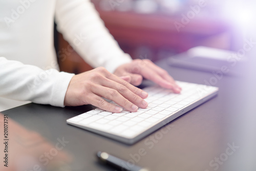 financial advisor typing on keyboard while sitting at office and working on computer - filter applied