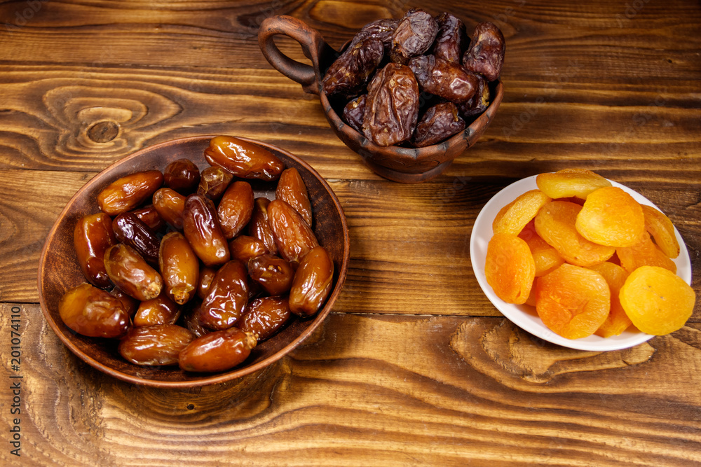 Dried apricots and dates fruit on wooden table Dried apricots and dates fruit on wooden table