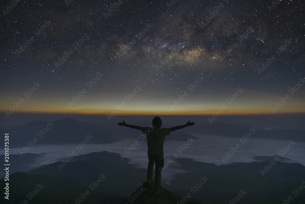 The milky way galaxy stars  and sunrise landscape of foggy and Man standing on the mountain and enjoying beautiful view. Freedom concept