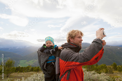 Male hiker with son photographing mountain landscape, Jotunheimen National Park, Lom, Oppland, Norway photo