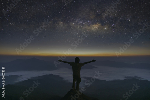 The milky way galaxy stars and sunrise landscape of foggy and Man standing on the mountain and enjoying beautiful view. Freedom concept