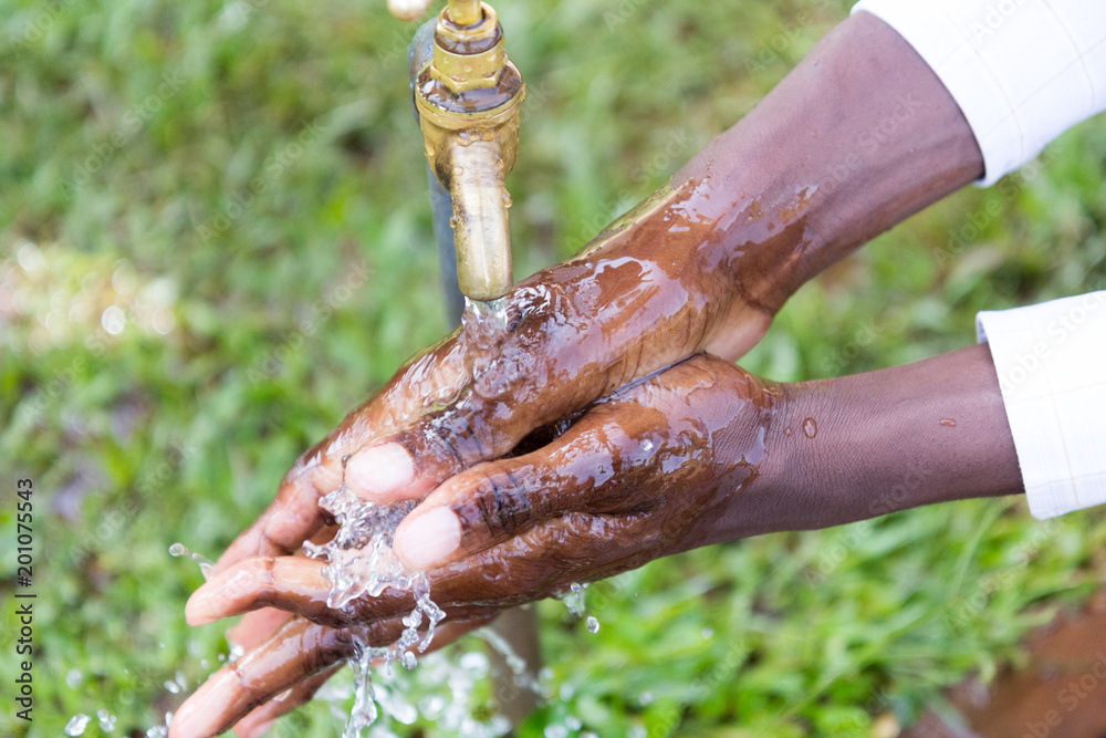 Ugandan children washing their hands at an outdoor water tap Stock