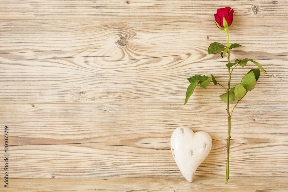 Eine rote Rose mit einem Herz vor einem Holz Hintergrund
