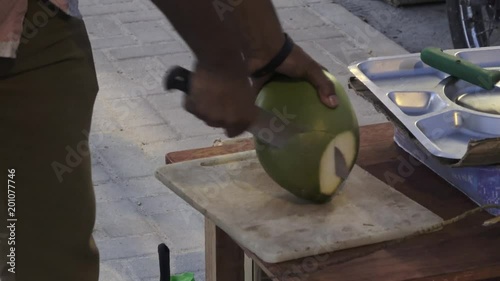 Man cuts off pieces from a young fresh coconut. Maldives video partial blurring