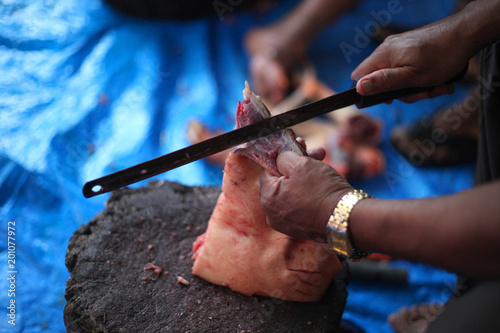 Butcher cut raw meat of a pig with a knife at table in the slaughterhouse