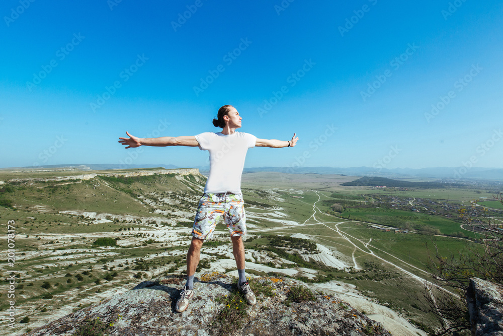 Photo of young handsome serious man standing over mountains and looking aside