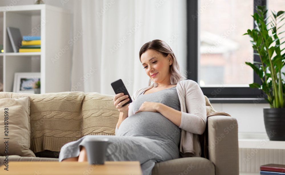 pregnancy, people and technology concept - happy pregnant woman with smartphone at home pregnancy, people and technology concept - happy pregnant woman with smartphone at home