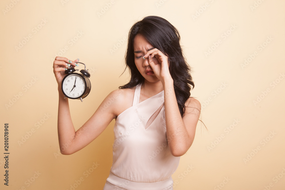 Sleepy young Asian woman with a clock in the morning. Sleepy young Asian woman with a clock in the morning.