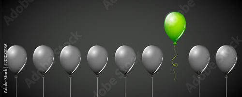 ein grüner luftballon unter vielen schwarzen