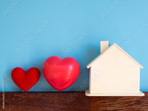 Red heart with wooden house on blue background (isolated). copy space for text and content. concept of love and family