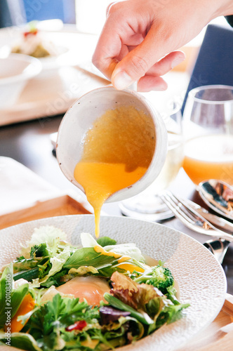 Fotografia Pouring cream vinaigrette dressing on mix salad dish