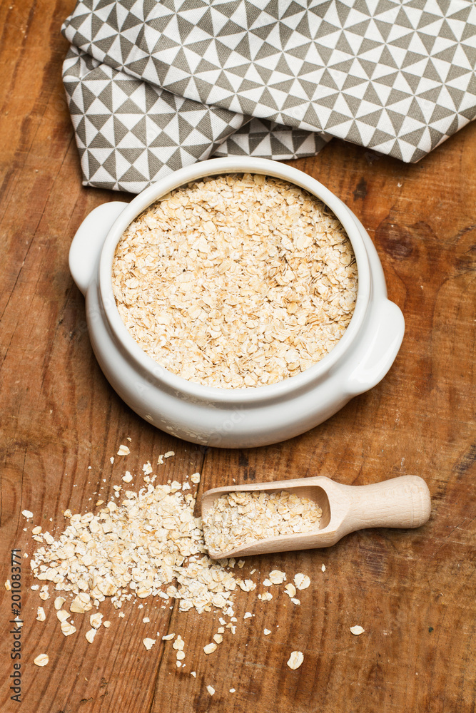 Avena dentro de un cuenco blanco junto a una cuchara pala sobre un fondo de madera rústico. Vista superior y de cerca. Formato vertical Avena dentro de un cuenco blanco junto a una cuchara pala sobre un fondo de madera rústico. Vista superior y de cerca. Formato vertical
