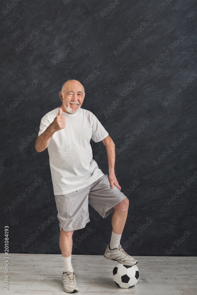 Senior man with soccer ball showing thumb up