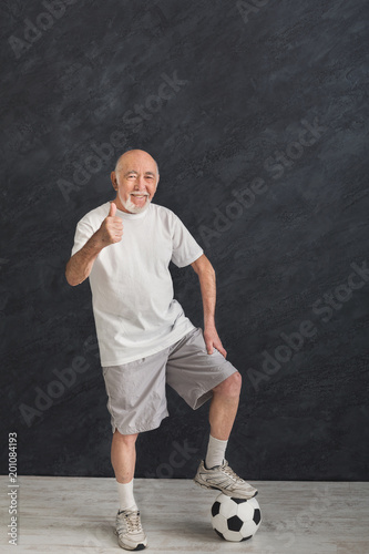 Senior man with soccer ball showing thumb up