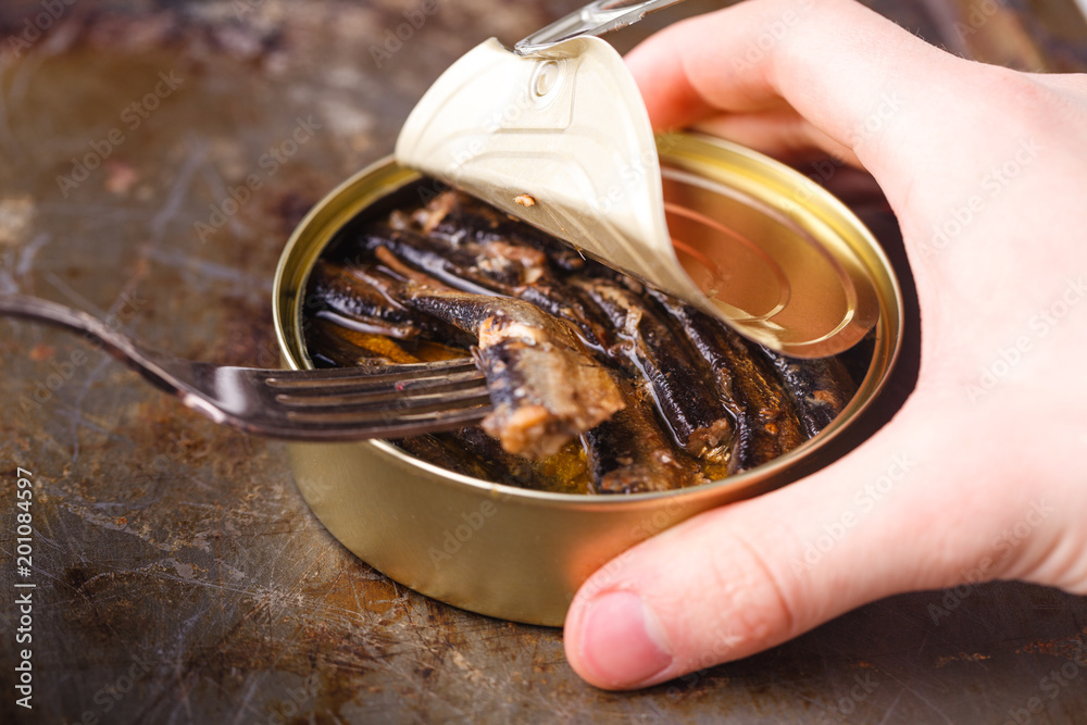 Fish can with can opener on wooden table Fish can with can opener on wooden table