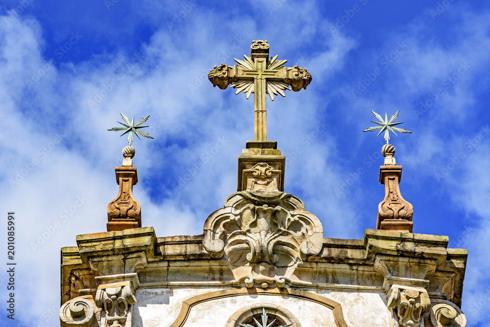 Baroque style crucifix and others ornaments on top of ancient and historical church in the city of Ouro Preto in Minas Gerais