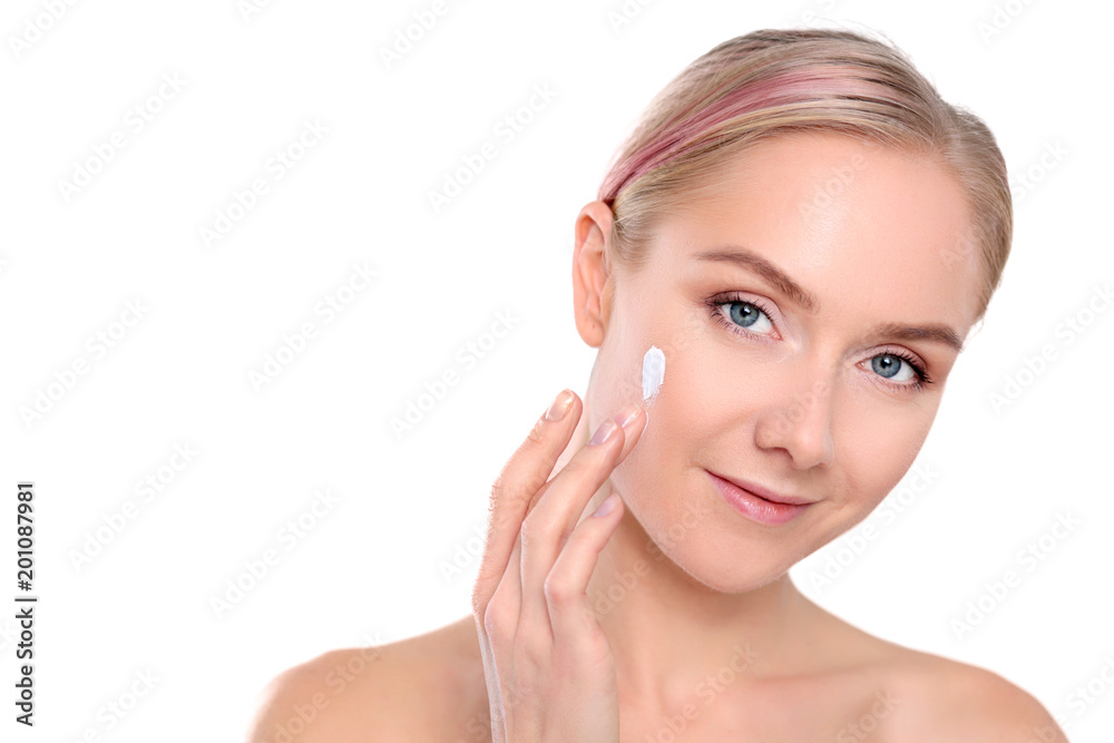 Portrait of happy smiling beautiful young woman touching skin or applying cream, isolated over white background