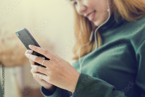 woman is listening music by her smartphone and feeling chill. Close-up of her phone