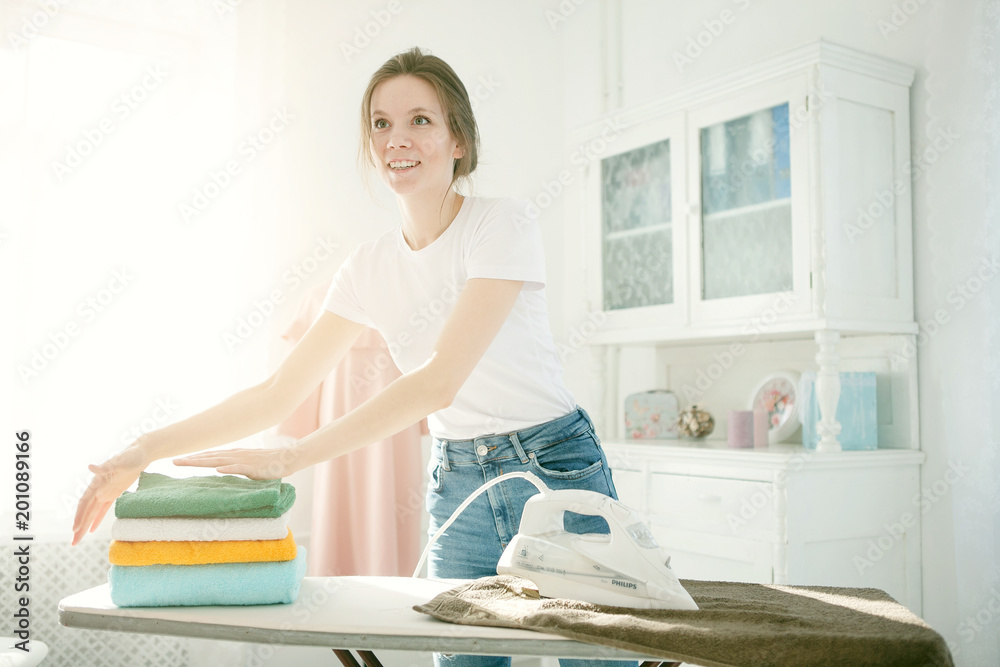 Young Smiling Woman Ironing Clothes On Ironing Board At Home Young Smiling Woman Ironing Clothes On Ironing Board At Home