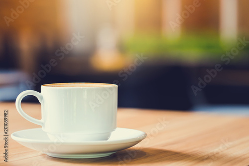 Latte Coffee in a cup on wooden table and Coffee shop blur background