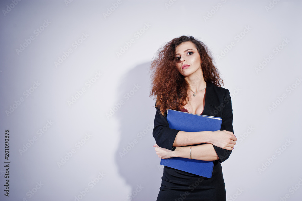 Brunette curly haired girl in black office jacket with skirt, on bra with folder of documentts at hands on studio against white background. Sexy businesswoman. Brunette curly haired girl in black office jacket with skirt, on bra with folder of documentts at hands on studio against white background. Sexy businesswoman.