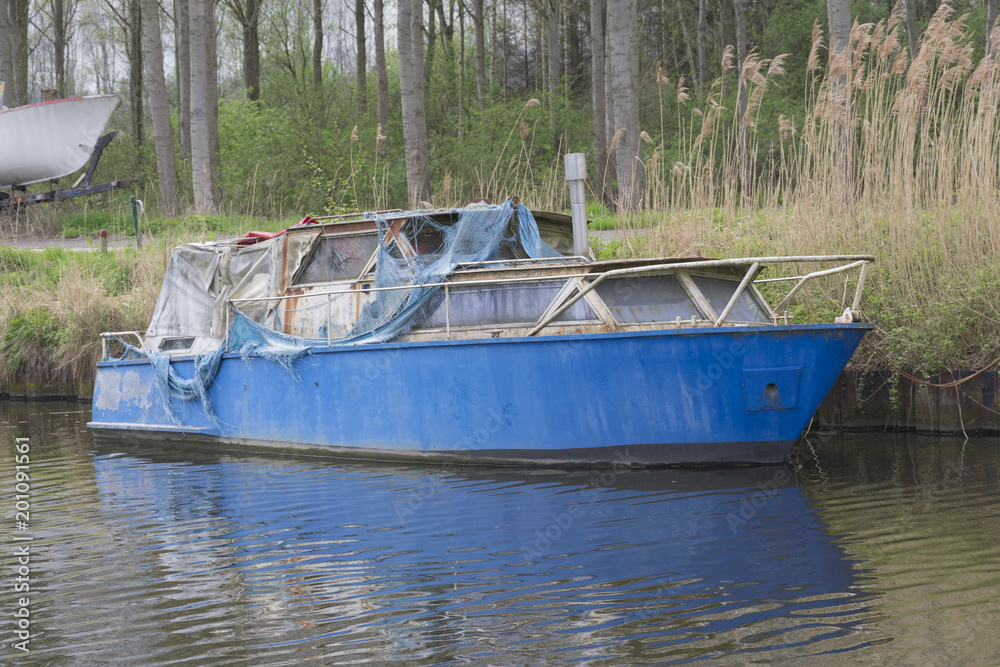 An old blue boat reflects in the water An old blue boat reflects in the water