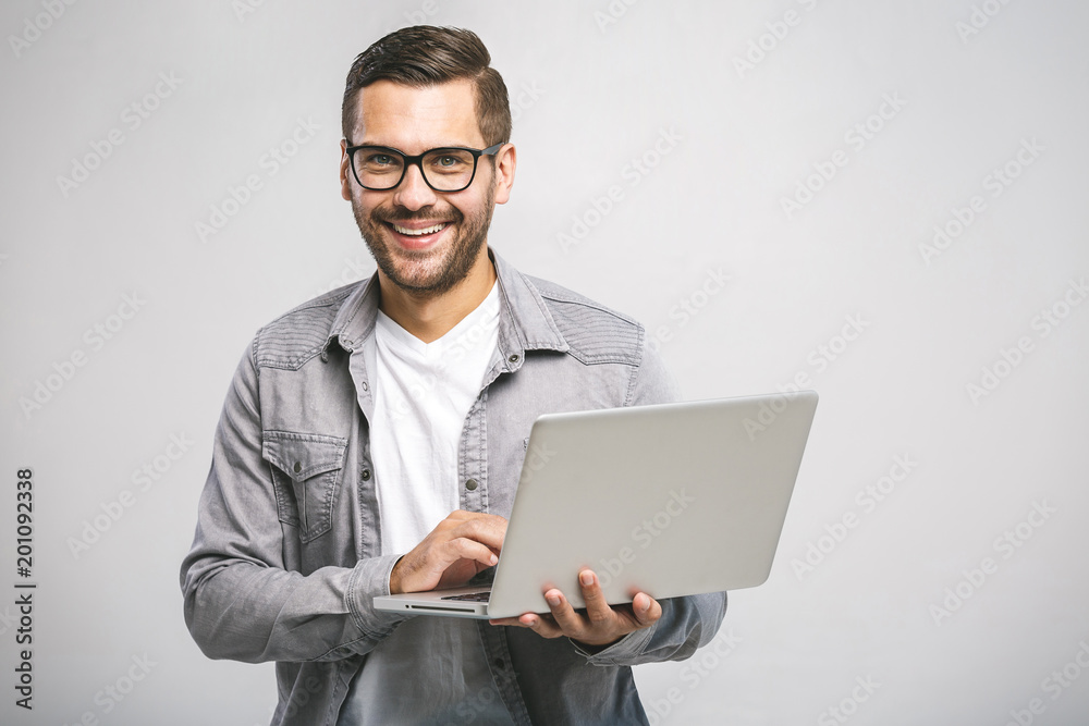 Confident business expert. Confident young handsome man in shirt holding laptop, looking at camera and smiling while standing against white background