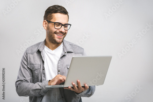 Confident business expert. Confident young handsome man in shirt holding laptop and smiling while standing against white background