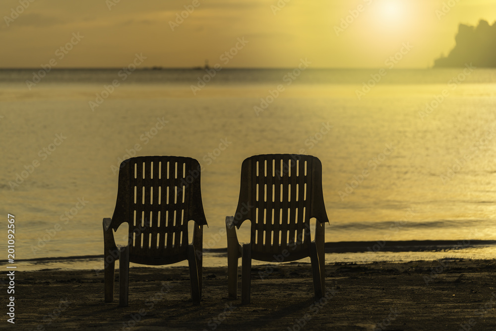 empty duo chairs on the beach on sunset