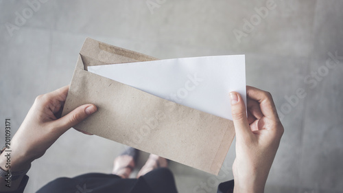 Stand up woman holding white folded a4 paper and brown envelope photo