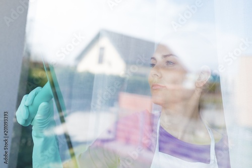 Young beautiful woman in white apron cleaing windows. photo