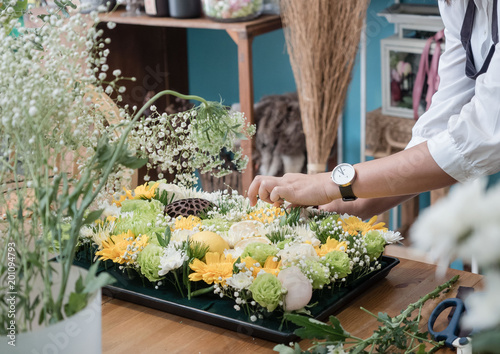 female hands arranging flower tray on wooden table