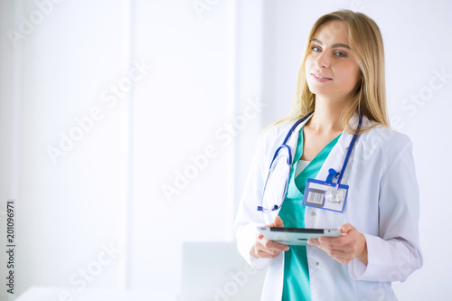 portrait of a young female doctor, with aipads in hand, in a medical office