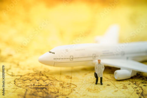 Business and global worldwide concept. Businessman miniature figure with suitcase and jacket standing on world map with airplane toy model as background