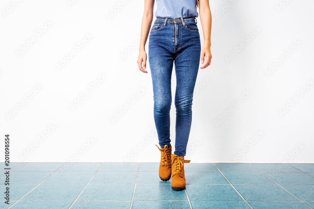 Young girl blue jeans brown shoes wall white. Stock-Foto | Adobe Stock