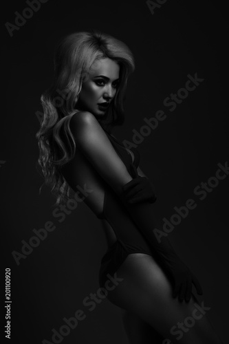 black and white photo of a girl in a swimsuit on a dark background.